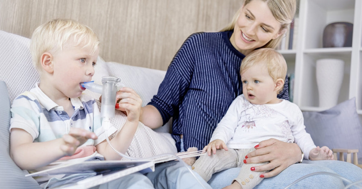 Mom with two children using a handheld nebulizer