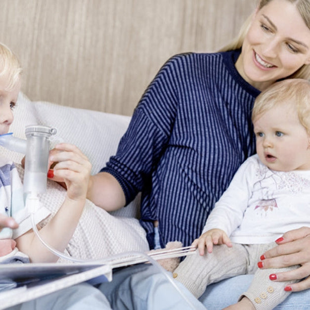 Mom with two children using a handheld nebulizer